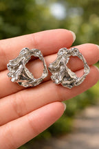 Anti-Tarnish, Ashaarya, Ashaarya Jewels, Ashaarya Jewellery, Silver earrings held in a hand with a blurred green background