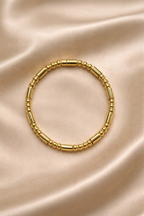 Ashaarya, Ashaarya jewels, ashaarya jewellery, charm bracelets, Gold beaded bracelet on a beige satin background