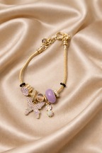 Charm bracelet, ashaarya, ashaarya bracelets, ashaarya jewels, ashaarya jewellery,Gold bracelet with charms on a beige satin background